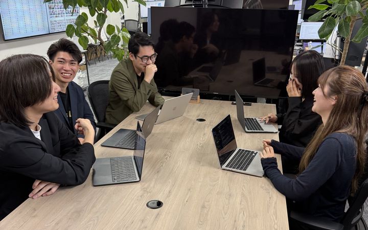 大きなテーブルで打ち合わせをするメンバー